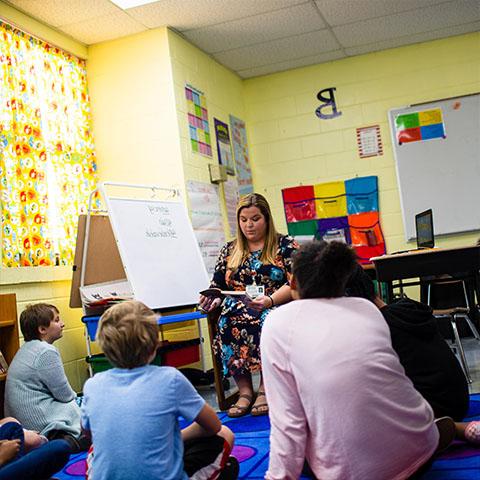 Student reads to kids in a classroom